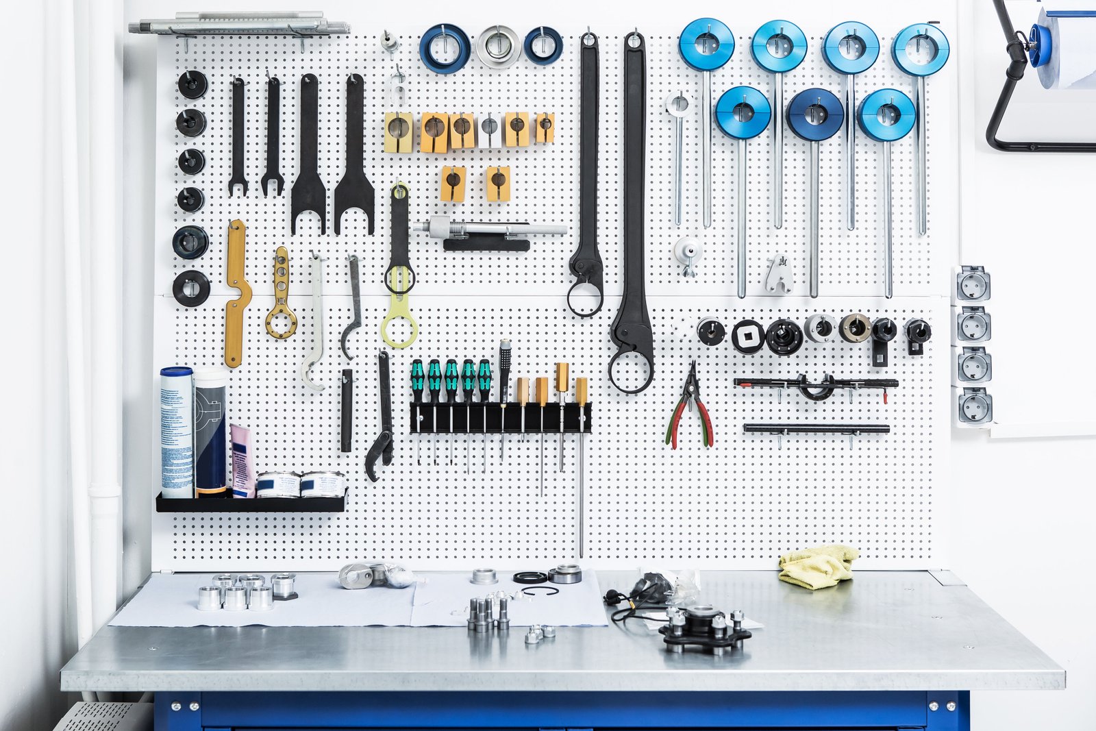 Modern professional repair workshop interior with organized tool racks, diagnostic equipment, clean stainless workbenches and blue LED accent lighting, shot wide angle